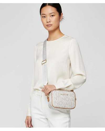 Modelo llevando bolso bandolera beige Valentino Regina RE con correa ancha logo