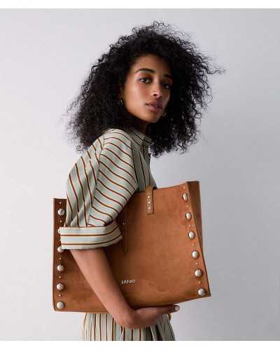 Modelo llevando al hombro bolso tote marrón Liu Jo Doba con tachuelas plateadas