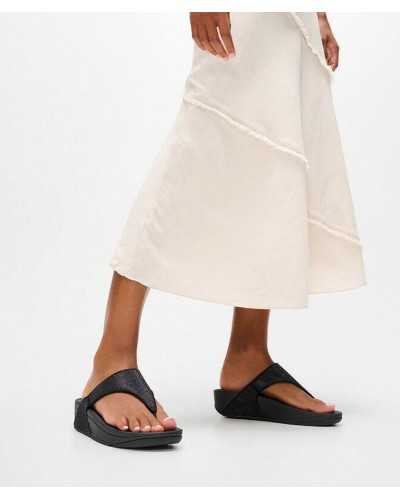 Sandalias FitFlop Lulu Shimmerglitz negras puestas con vestido blanco roto