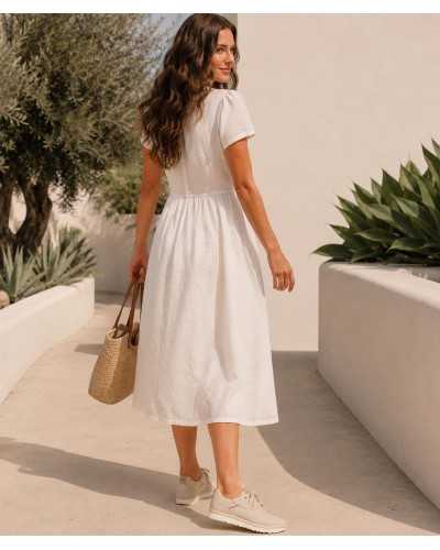 Mujer con zapatillas UGG color crema y vestido de lino blanco en look verano mediterráneo