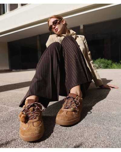 Modelo con sneakers Noa Harmon TEN color cuero, pantalón de raya diplomática y gabardina beige