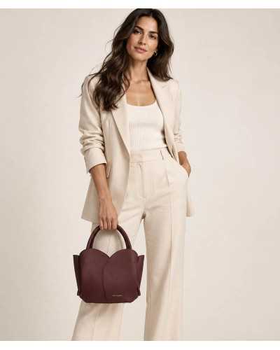 Mujer con traje beige llevando el bolso Roselle burdeos de Noa Harmon