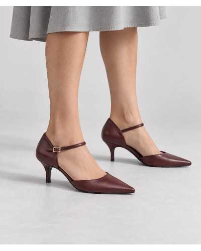 Mujer con falda midi gris y salones burdeos de tacón kitten con pulsera y hebilla dorada
