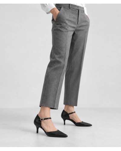 Mujer con falda midi gris y salones negros de tacón kitten con pulsera y hebilla dorada