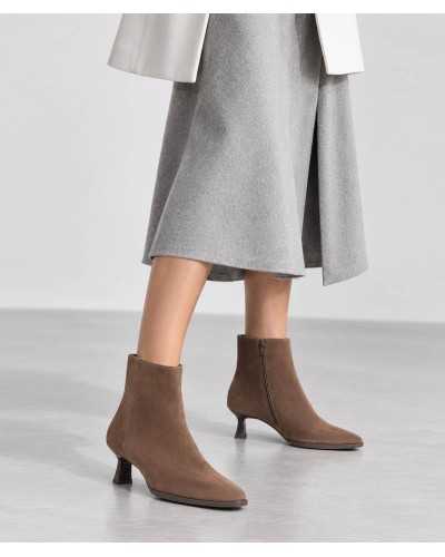 Botines Unisa Lomas taupe puestos con falda midi gris y abrigo blanco