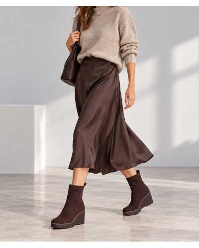 Mujer con botines de cuña marrón chocolate, falda midi satinada marrón, jersey de punto beige y bolso marrón
