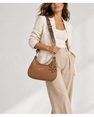 Mujer con vaqueros pitillo y salones negros llevando en la mano el bolso hobo Liu Jo camel por su asa de cadena