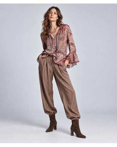 Mujer con blusa de estampado paisley en tonos burdeos, pantalón ancho marrón con puño fruncido y botines de serraje chocolate