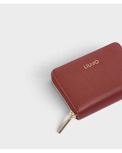 Detalle del logo dorado y la cremallera de la cartera Liu Jo burdeos sobre piel sintética granulada