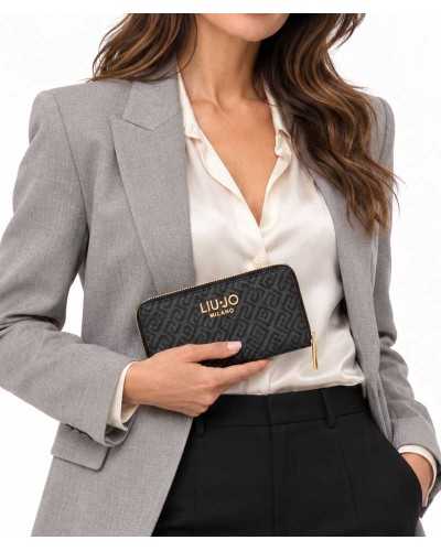 Cartera grande Liu Jo negra con monograma en la mano de una modelo