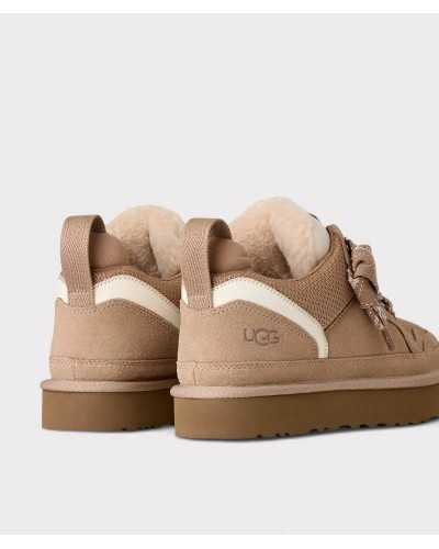 Par de zapatillas UGG Lowmel beige por detrás, con tirador de cinta y logo grabado